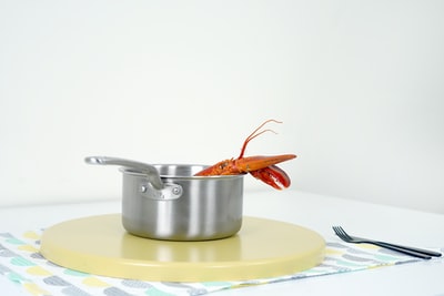 Boiled lobster on grey stainless steel pot, stainless steel fork near the gray
